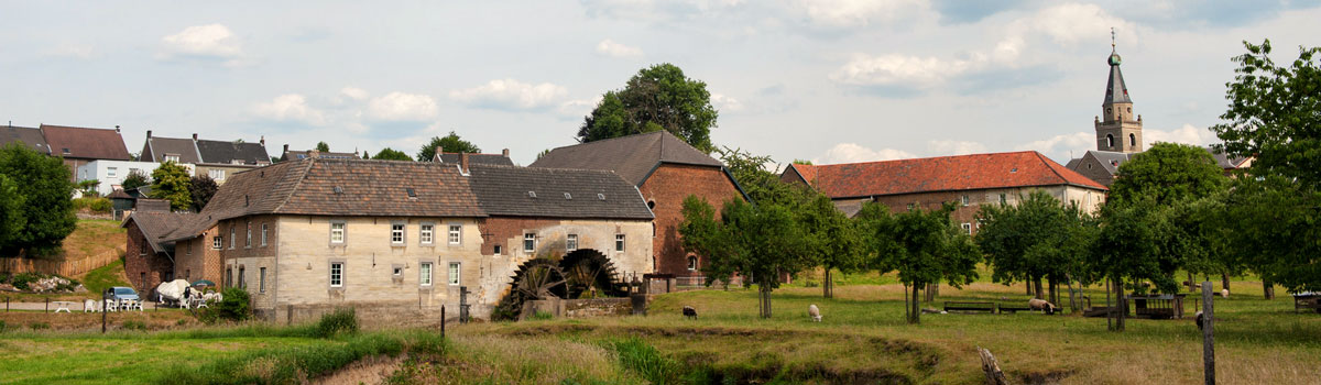 Headerfoto met Zuid limburgs dorpje kerk, boerderijen en watermolen